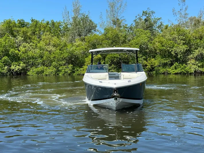  Yacht Photos Pics 2020 Cobalt R30 boat cruising on a calm river with lush greenery in the background.