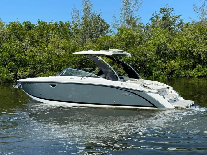  Yacht Photos Pics 2020 Cobalt R30 boat cruising on a calm river with lush greenery in the background.