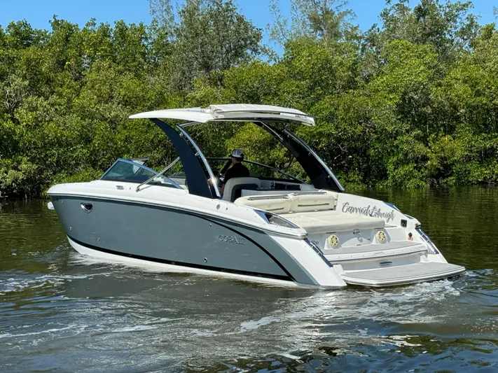  Yacht Photos Pics 2020 Cobalt R30 boat cruising on a calm river with lush greenery in the background.