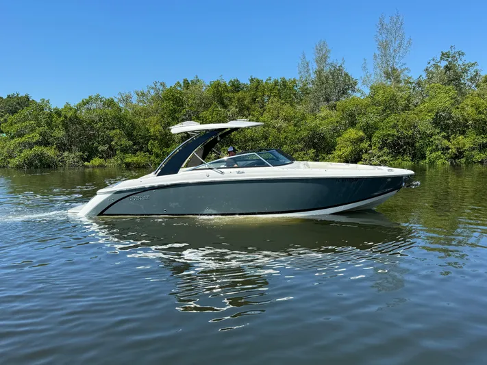  Yacht Photos Pics 2020 Cobalt R30 boat cruising on a calm river with lush greenery in the background.