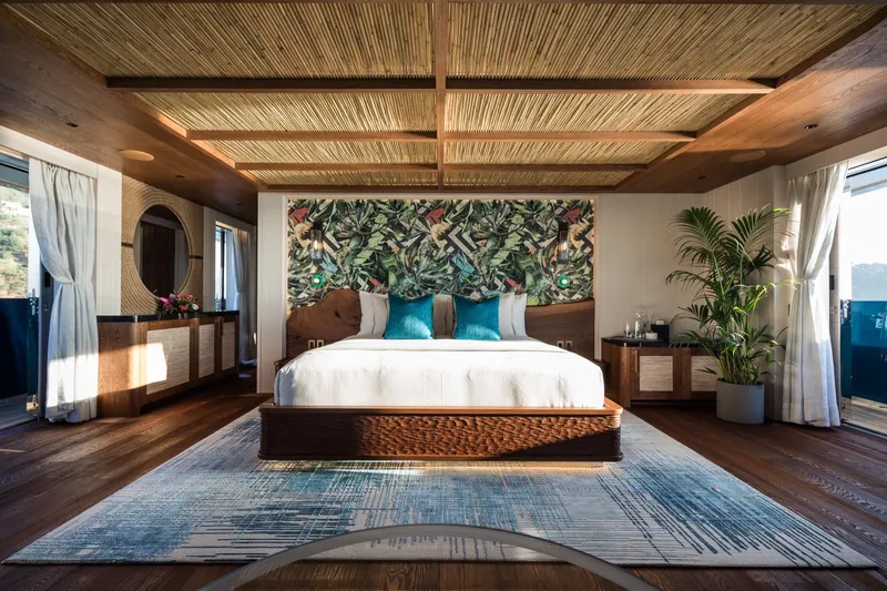 King Benji Yacht Photos Pics Luxurious Dunya Yachts 2024 bedroom with tropical decor, elegant furnishings, and natural lighting.