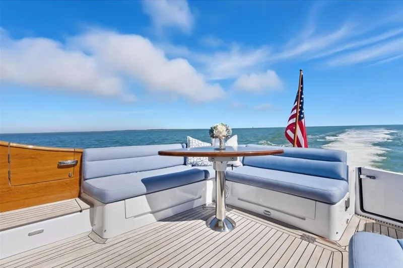 Jeannius II Yacht Photos Pics 2015 Hinckley Talaria 43 yacht deck with seating, table, and American flag on open sea.