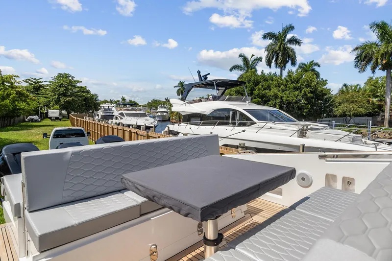  Yacht Photos Pics 2023 Astondoa 377 Coupe Outboard yacht with luxurious seating and table, docked near other boats.