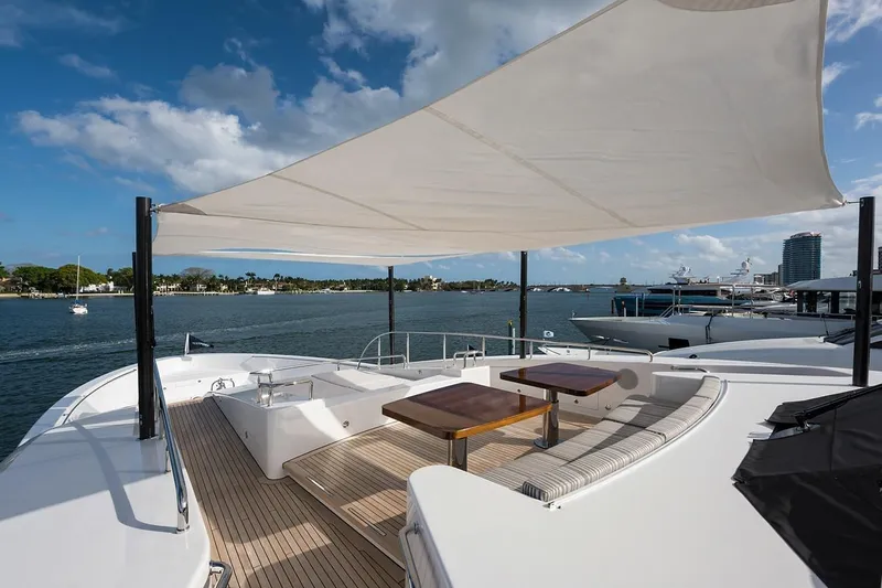 Serenity Yacht Photos Pics Luxurious 2018 Westport Raised Pilothouse yacht deck with seating and sunshade, overlooking serene waters.