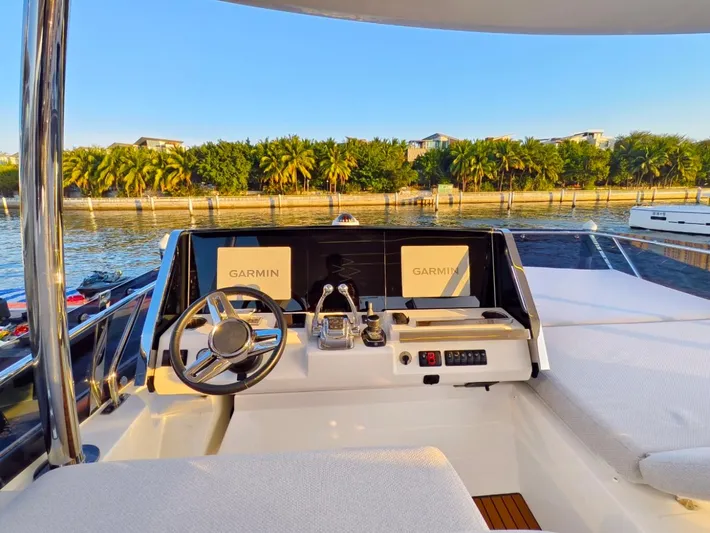  Yacht Photos Pics Helm of 2022 Prestige 590 yacht with Garmin displays, overlooking serene waterfront.