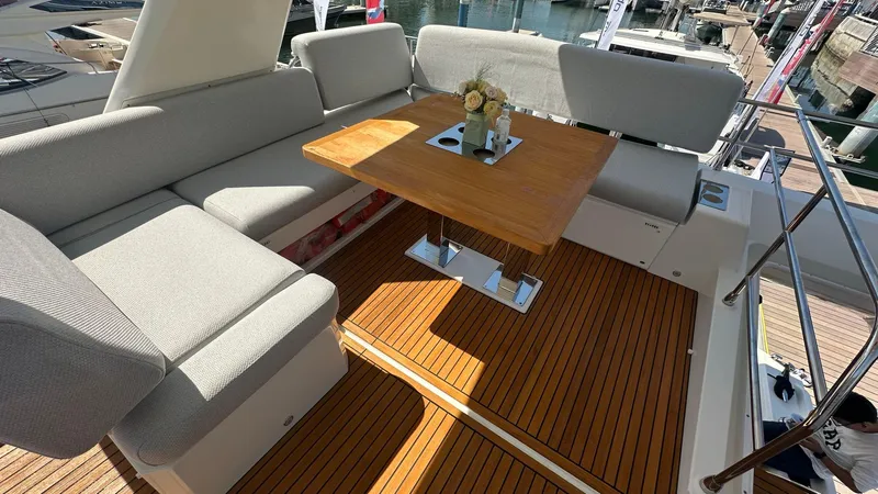  Yacht Photos Pics Luxurious seating area on 2022 Prestige 590 yacht with wooden table and cushions.