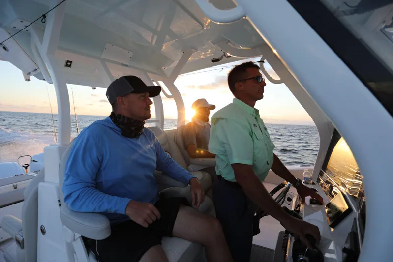 Black Label Marine Group Yacht Photos Pics Three men navigating a 2025 Sea Fox 368 Commander Center Console at sunset.