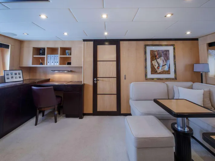 Ultim Yacht Photos Pics Luxurious yacht interior with modern decor, featuring a desk, seating area, and elegant artwork.