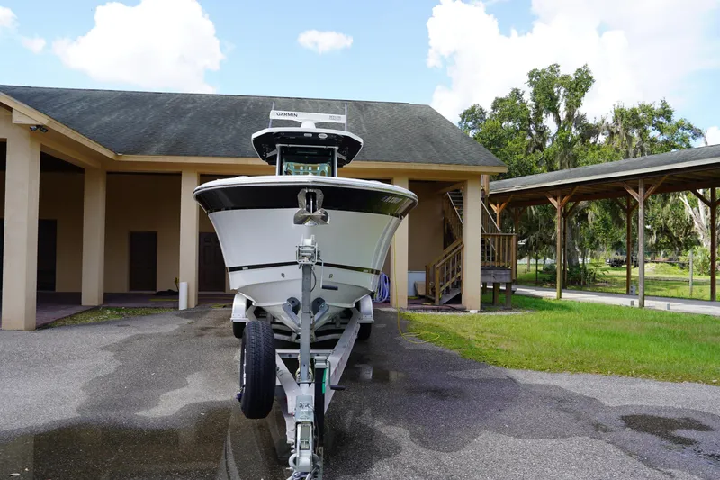  Yacht Photos Pics 2023 Blackfin 302 CC boat on trailer, parked near a building with trees in the background.