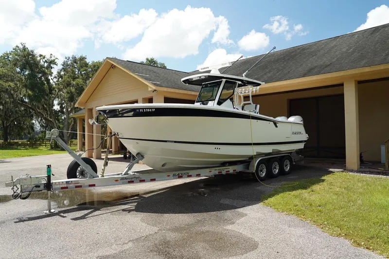 Yacht Photos Pics 2023 Blackfin 302 CC boat on a trailer, parked near a house under a clear sky.