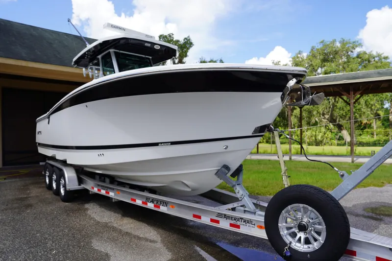  Yacht Photos Pics 2023 Blackfin 302 CC boat on trailer, parked outdoors, showcasing sleek design.