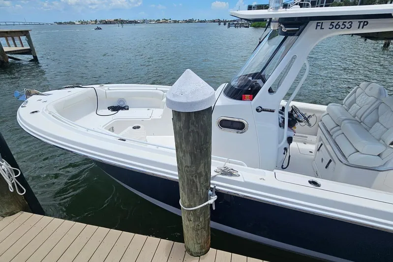  Yacht Photos Pics 2023 Edgewater 262CC boat docked by the water, featuring sleek design and comfortable seating.