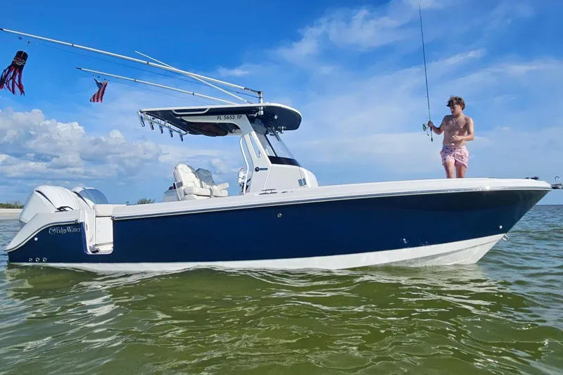  Yacht Photos Pics 2023 Edgewater 262CC boat with person fishing, set against a clear blue sky.