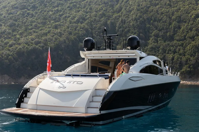 Infinito Yacht Photos Pics 2007 Sunseeker Predator 82 yacht on serene water, surrounded by lush greenery.