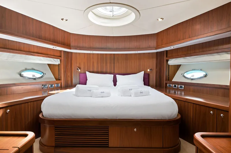 Infinito Yacht Photos Pics Luxurious bedroom interior on 2007 Sunseeker Predator 82 yacht, featuring elegant wood paneling.