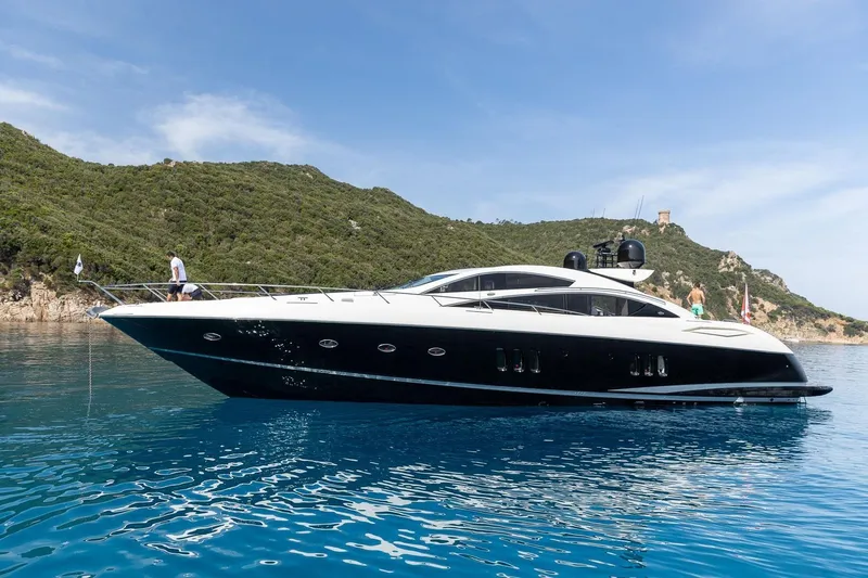 Infinito Yacht Photos Pics Luxury Sunseeker Predator 82 yacht, 2007 model, cruising in clear blue waters near a scenic coastline.