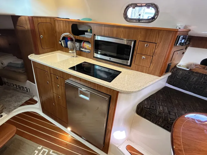  Yacht Photos Pics 2010 Pursuit OS 345 Offshore boat interior with kitchenette, featuring wood cabinetry and modern appliances.