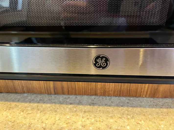  Yacht Photos Pics Stainless steel GE appliance with logo, set on a wooden and stone countertop.