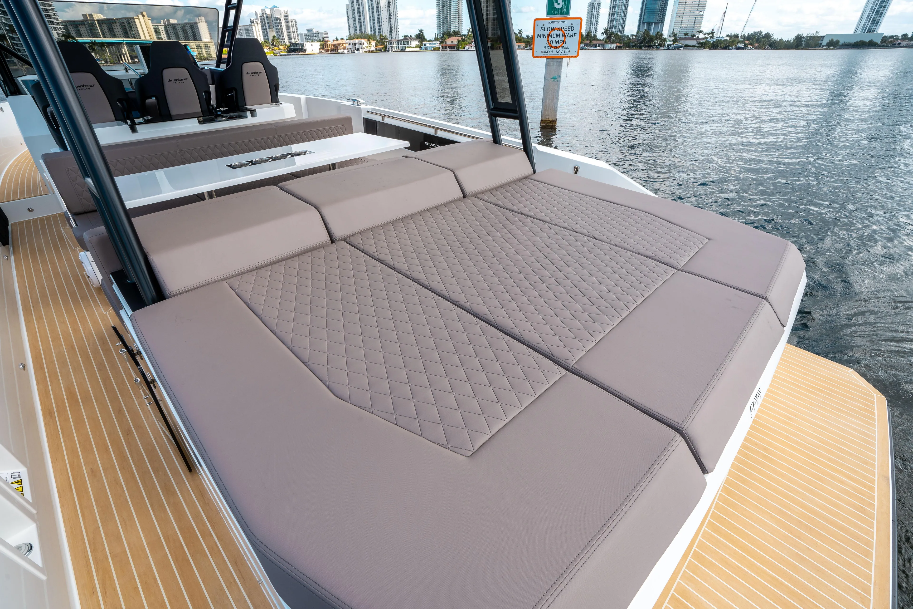  Yacht Photos Pics 2025 De Antonio Yachts D32 OPEN with spacious sunbed, docked by waterfront cityscape.