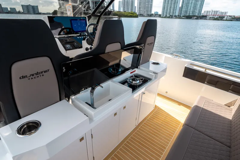  Yacht Photos Pics 2025 De Antonio Yachts D32 OPEN interior with modern kitchen and seating, overlooking waterfront cityscape.