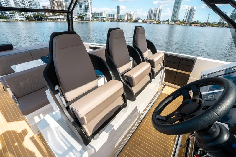  Yacht Photos Pics 2025 De Antonio Yachts D32 OPEN interior with modern seating and steering, overlooking city skyline.