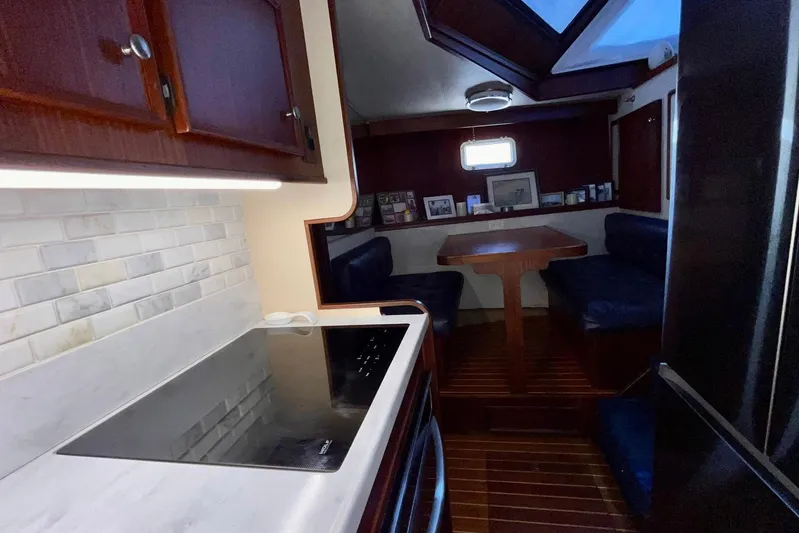 Rubber Ducky Yacht Photos Pics 1981 Hatteras 48 Motor Yacht interior with kitchen and dining area, featuring wood cabinetry and seating.