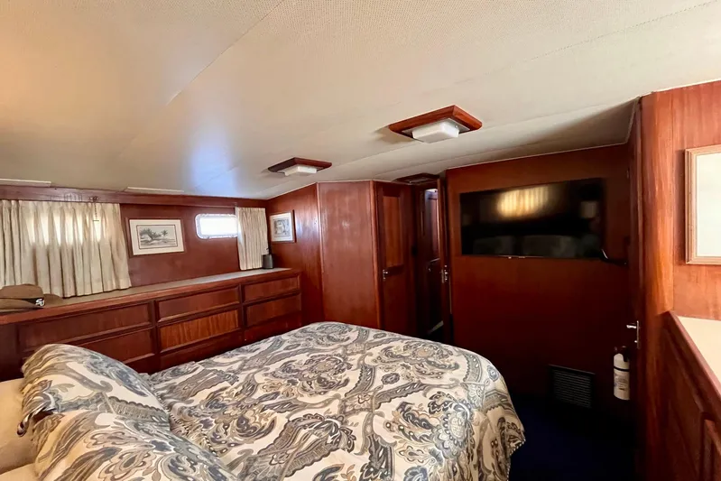 Rubber Ducky Yacht Photos Pics 1981 Hatteras 48 Motor Yacht bedroom with wood paneling, bed, and TV.