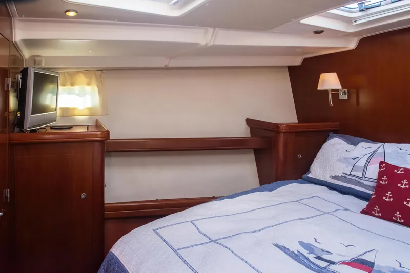  Yacht Photos Pics Cozy cabin interior of 2007 Beneteau Oceanis 523 with nautical-themed bedding and TV.