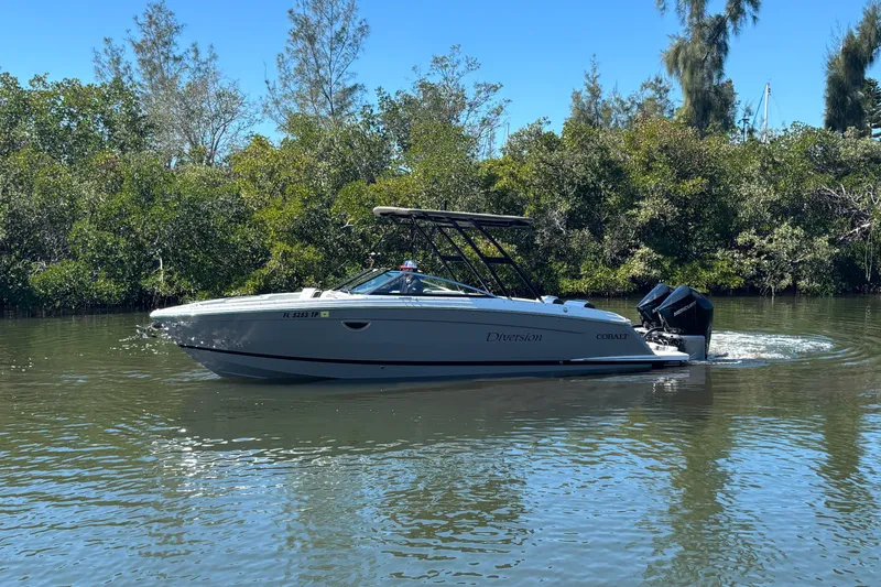  Yacht Photos Pics 2022 Cobalt R8 Outboard boat cruising on a calm river with lush greenery.