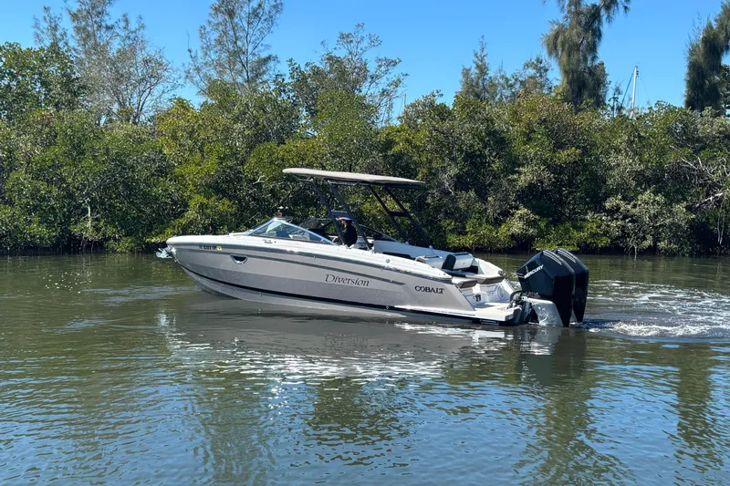  Yacht Photos Pics 2022 Cobalt R8 Outboard boat cruising on a calm river with lush greenery.