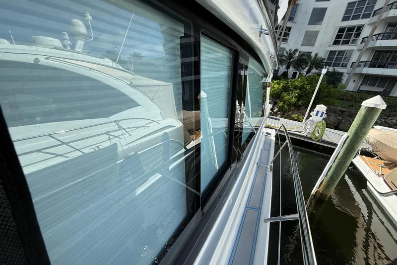  Yacht Photos Pics 2023 Regal 38 FXO yacht docked, reflecting on water, with modern buildings in the background.