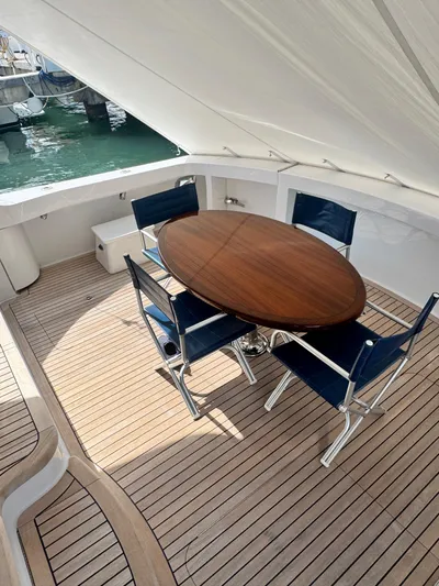  Yacht Photos Pics Outdoor seating area on 2011 Hatteras GT60 yacht with wooden table and blue chairs.