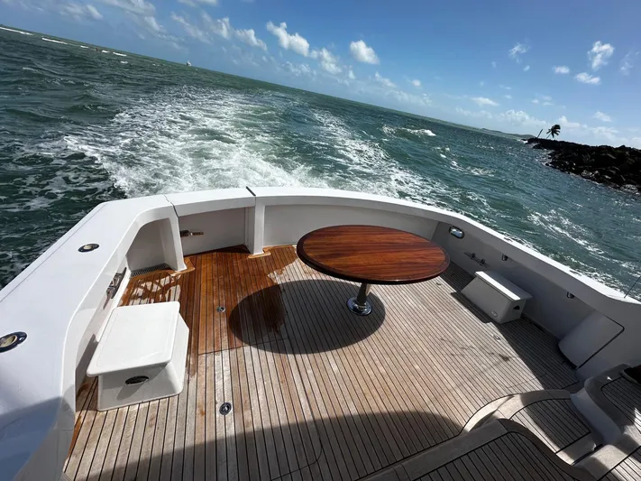  Yacht Photos Pics 2011 Hatteras GT60 yacht deck with wooden table, cruising on open sea.