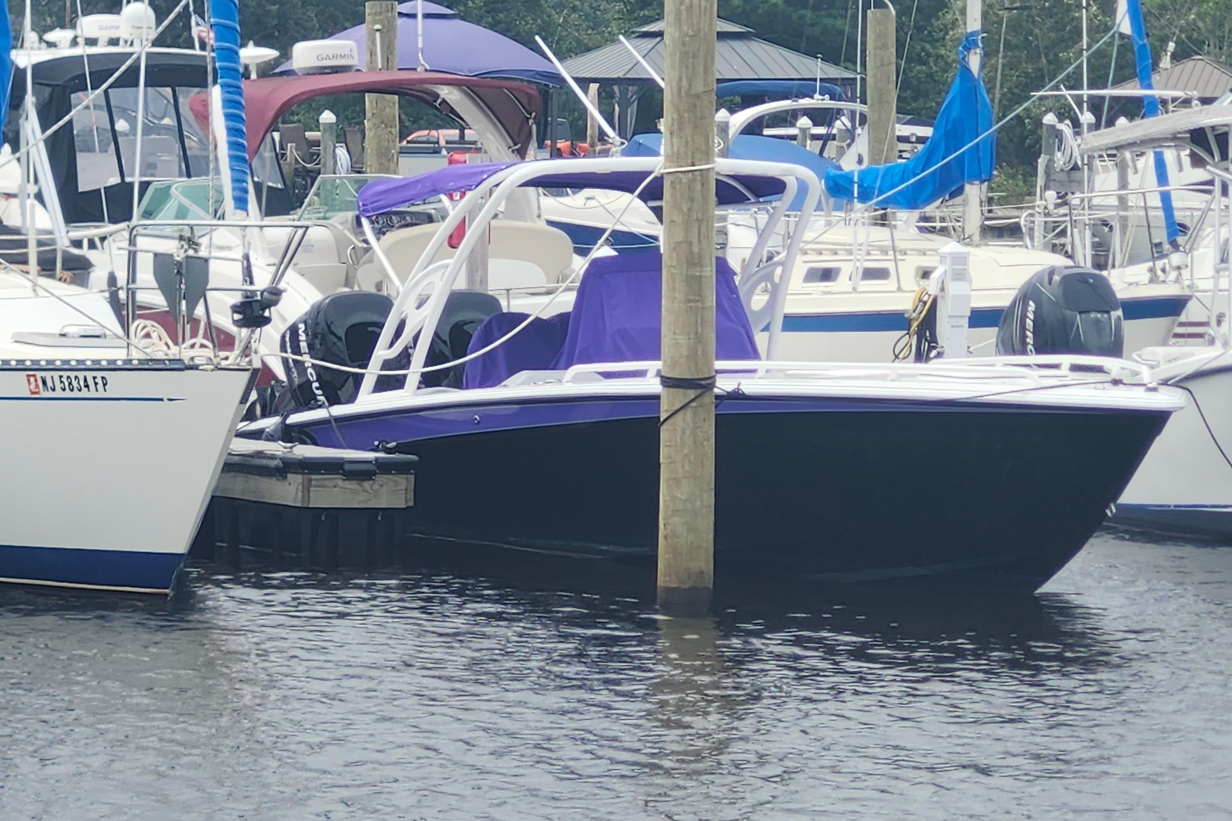 2014 Concept 30 Cuddy boat docked in a marina, surrounded by other vessels.