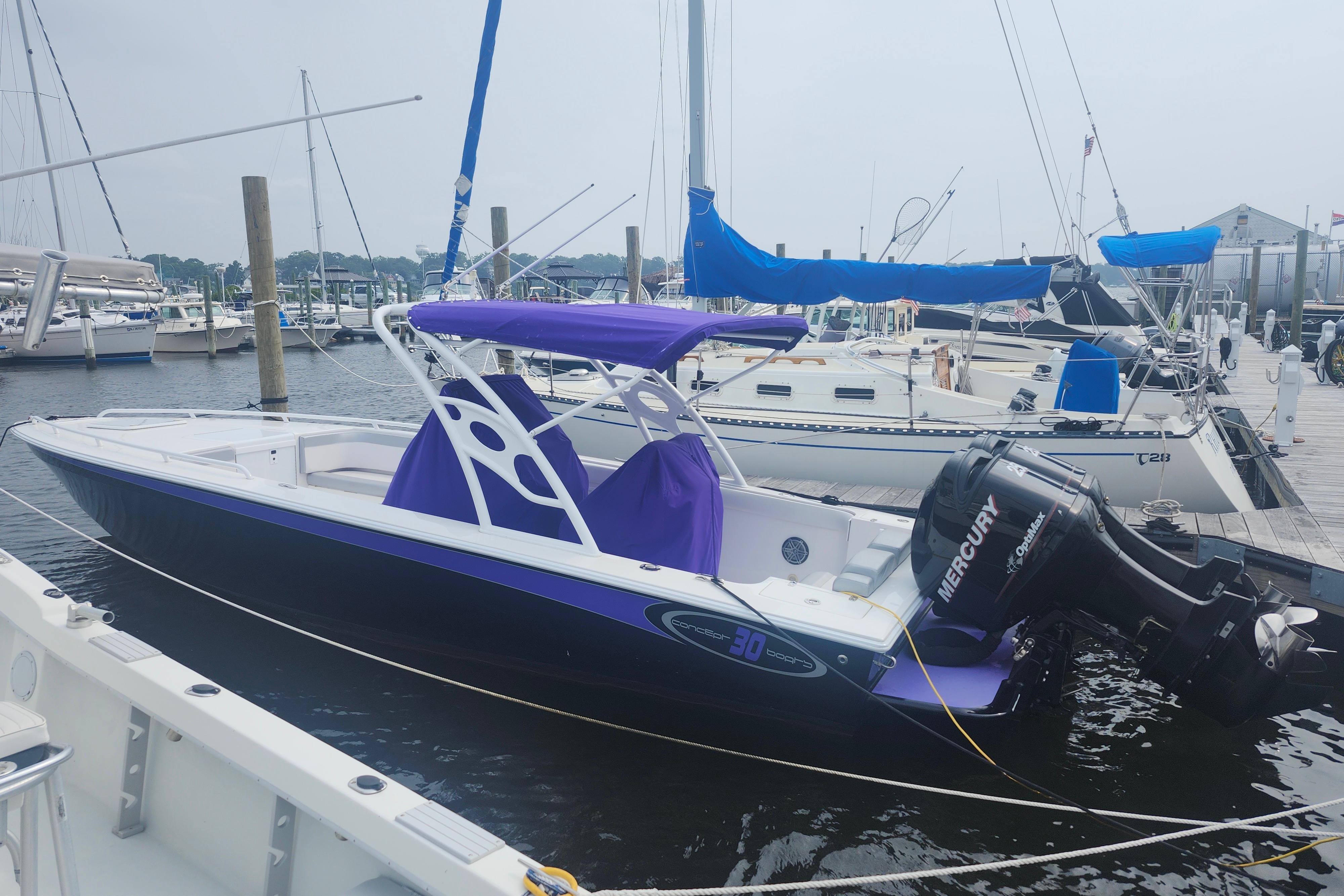 2014 Concept 30 Cuddy boat docked with purple canopy and Mercury outboard motor.