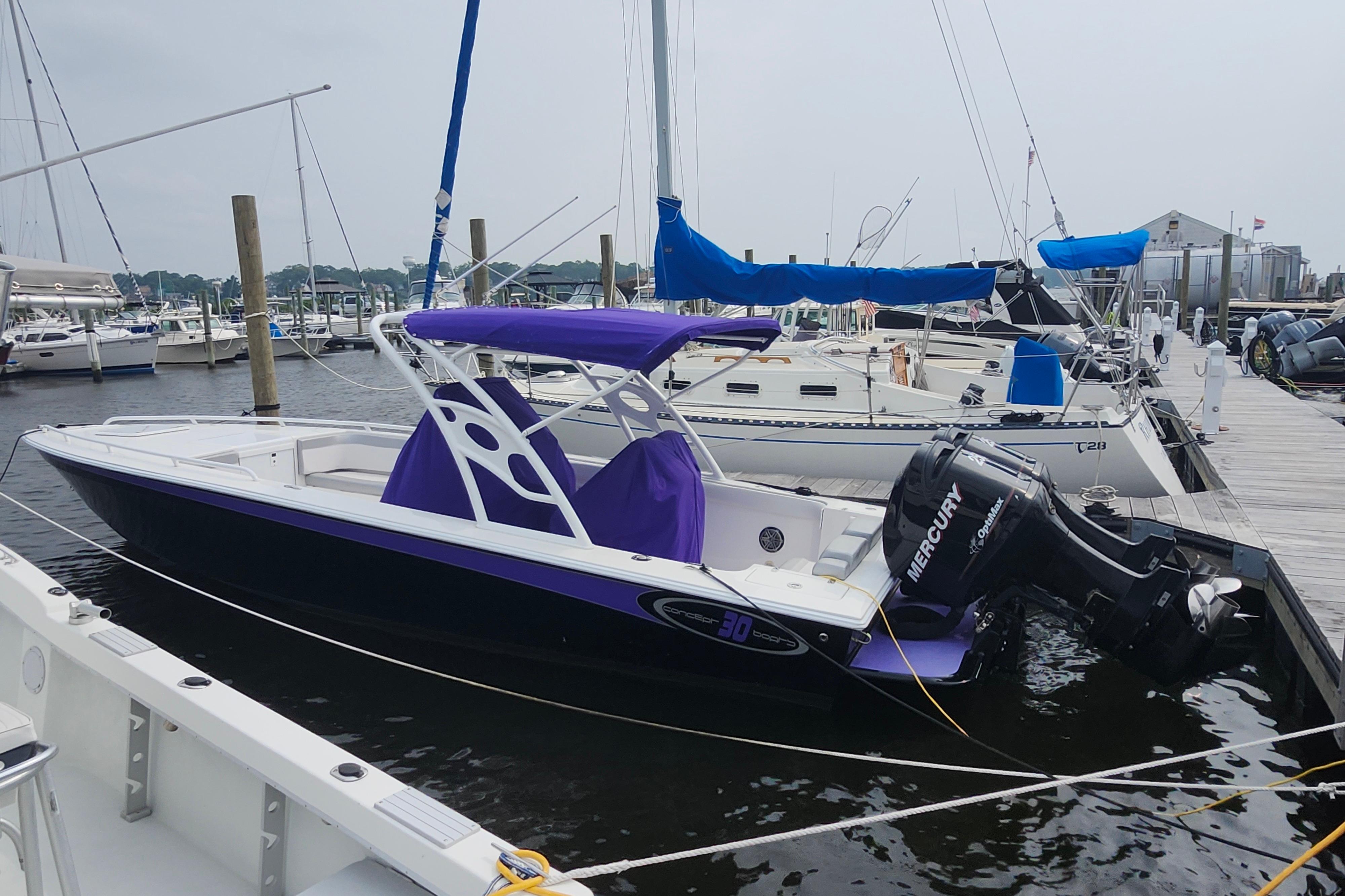 2014 Concept 30 Cuddy boat docked, featuring a purple canopy and Mercury outboard motor.
