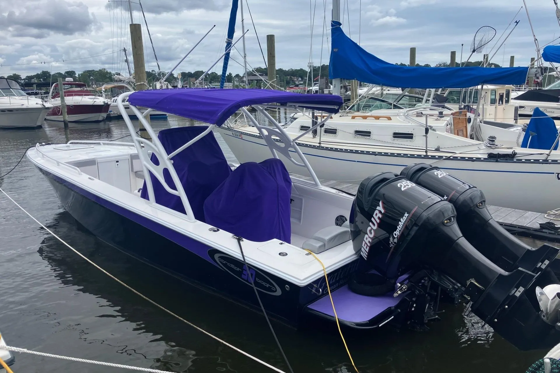 2014 Concept 30 Cuddy boat with purple canopy and twin Mercury engines docked at marina.