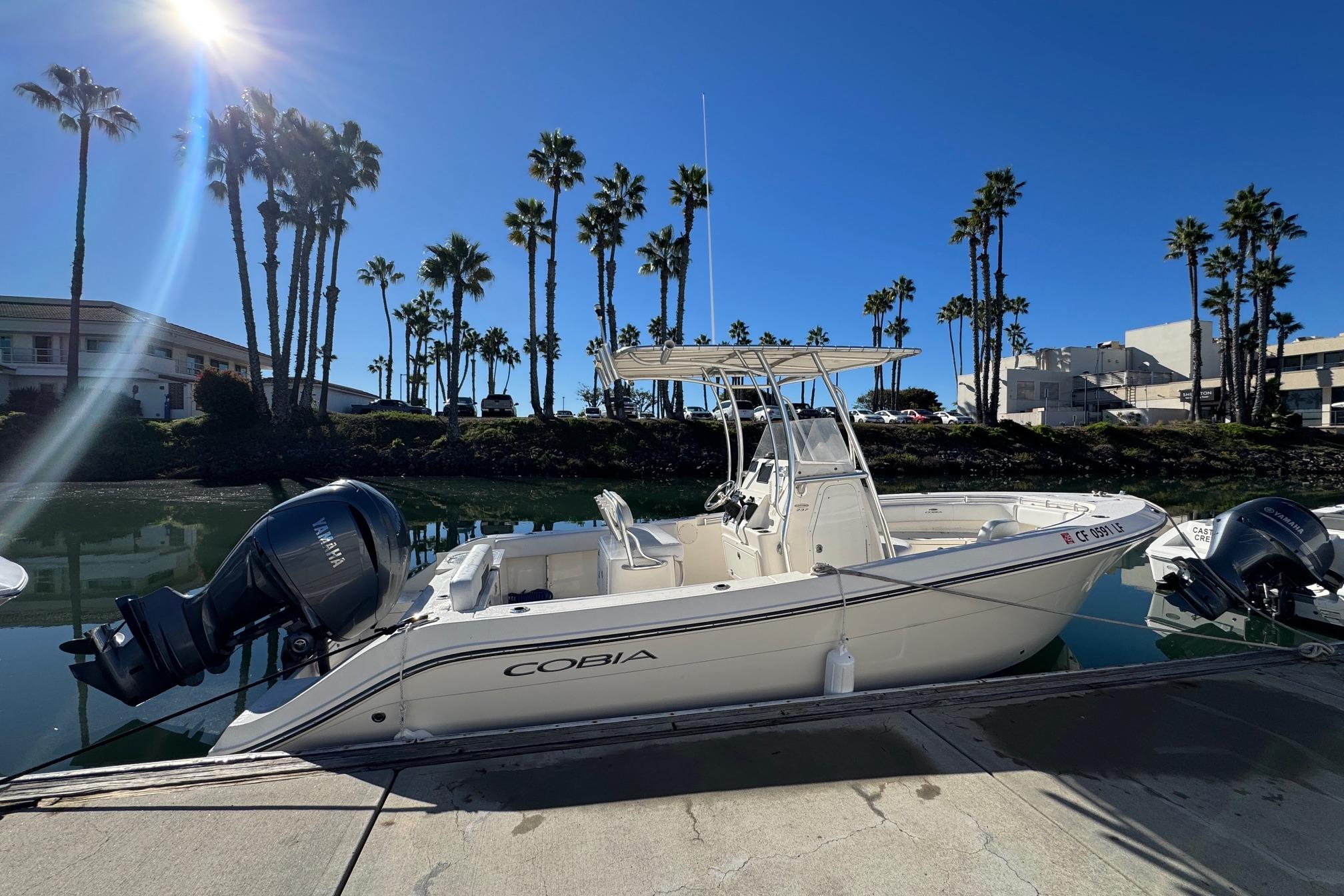 2022 Cobia 237 Center Console boat docked under clear blue sky.