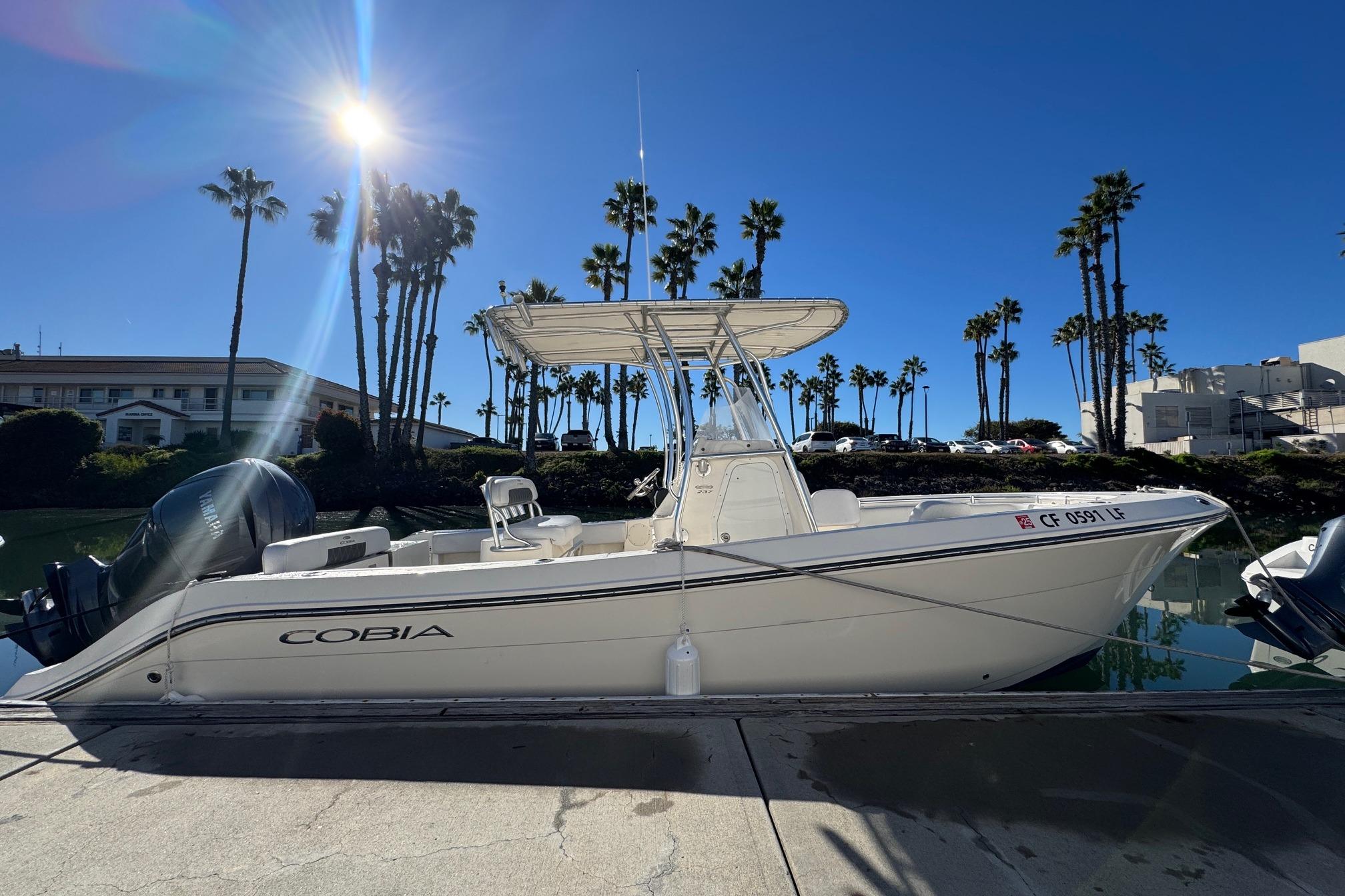 2022 Cobia 237 Center Console boat docked under clear blue sky.