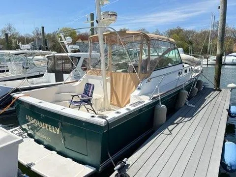  Yacht Photos Pics 1999 Sabreline 36 Express yacht docked at marina, featuring green hull and tan canopy.