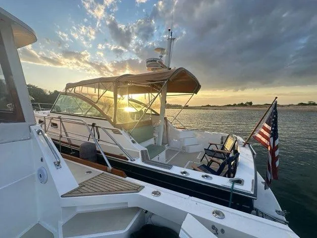  Yacht Photos Pics 1999 Sabreline 36 Express yacht at sunset, featuring American flag and scenic water view.