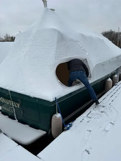  Yacht Photos Pics Man entering snow-covered 1999 Sabreline 36 Express boat in winter.
