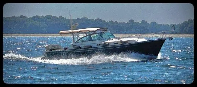  Yacht Photos Pics 1999 Sabreline 36 Express cruising on open water, with scenic shoreline in background.