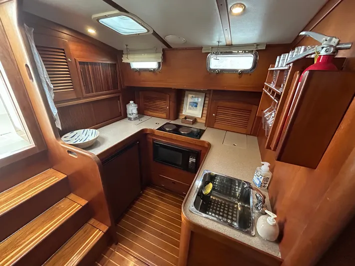  Yacht Photos Pics 1999 Sabreline 36 Express yacht kitchen with wood cabinetry, sink, microwave, and stairs.