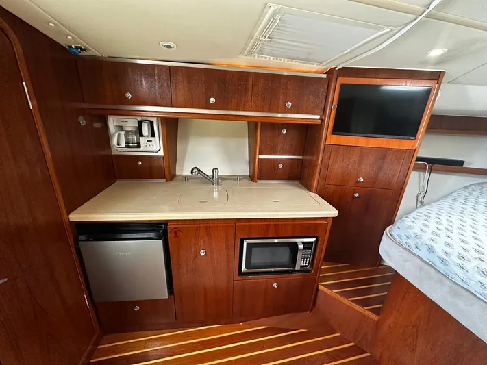  Yacht Photos Pics 2005 Tiara Yachts 3200 Open interior kitchen with wood cabinetry, microwave, and mini fridge.