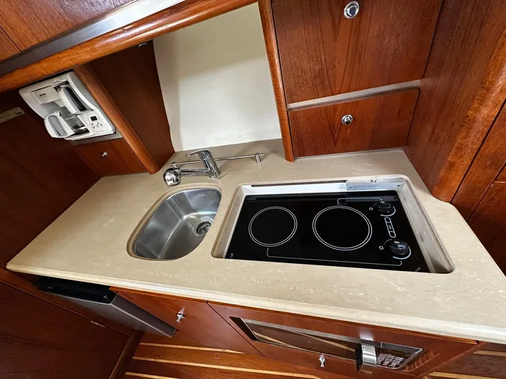  Yacht Photos Pics 2005 Tiara Yachts 3200 Open kitchen with stove, sink, and wooden cabinetry.