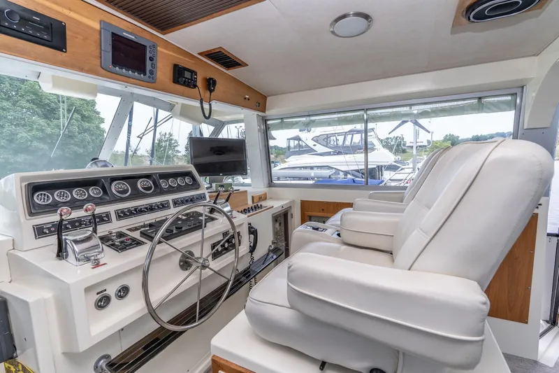 Tenacity Yacht Photos Pics Interior helm of 1986 Bertram 58 Flybridge Motor Yacht with modern controls and white seating.
