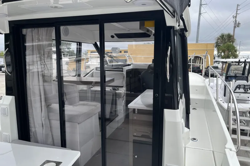 Yacht Photos Pics 2025 Jeanneau NC 895 Sport Series 2 boat interior with sliding glass doors and seating area.