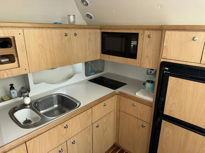 Superfishal II Yacht Photos Pics 1999 Tiara Yachts 4100 Open kitchen with wood cabinets, sink, microwave, and fridge.