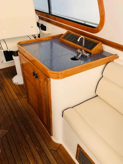 Sparrow Yacht Photos Pics 2004 Sabre 42 Hardtop Express interior with sink, wooden cabinetry, and cushioned seating.